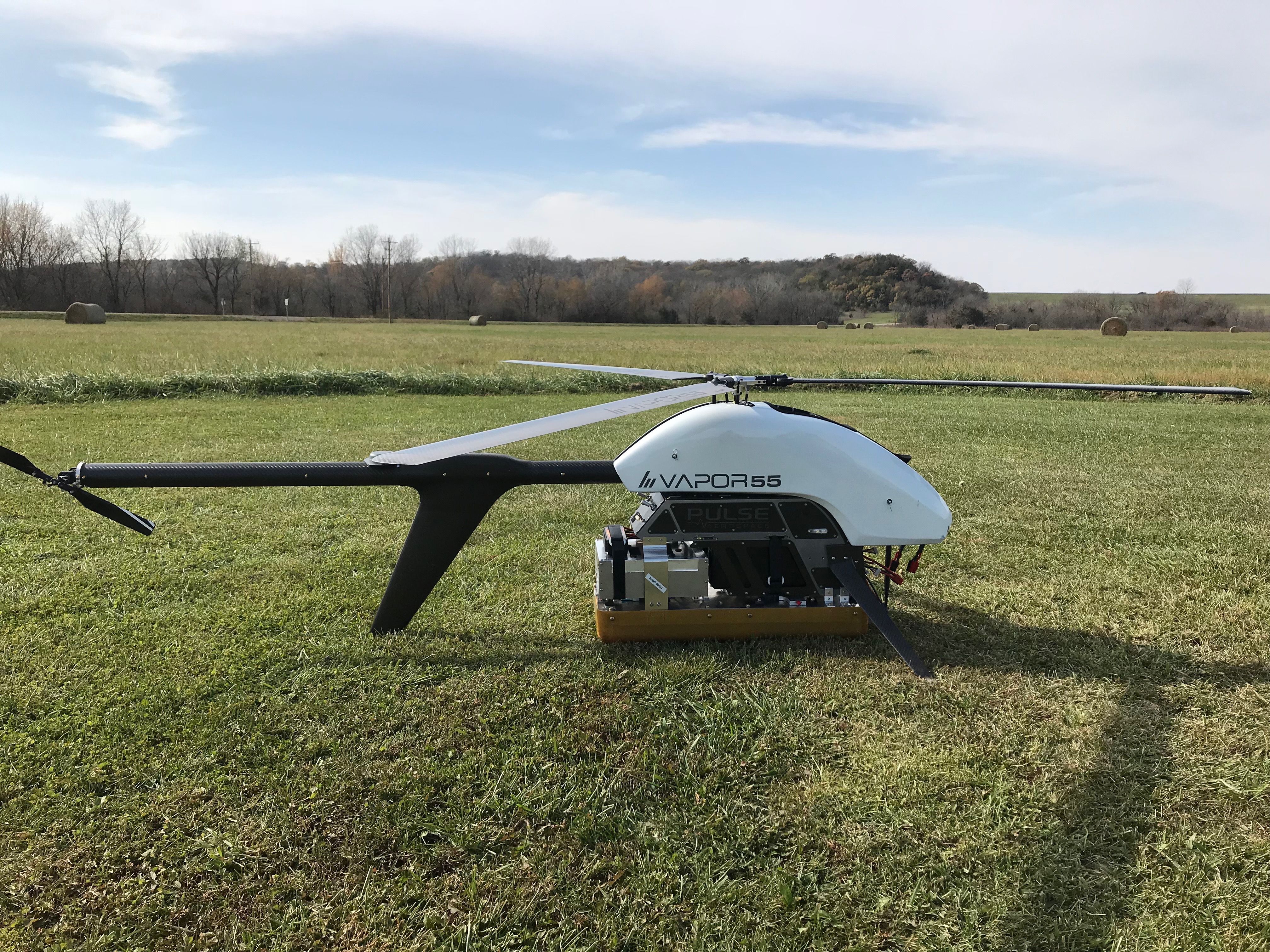 Helicopter flying over a grassy field.